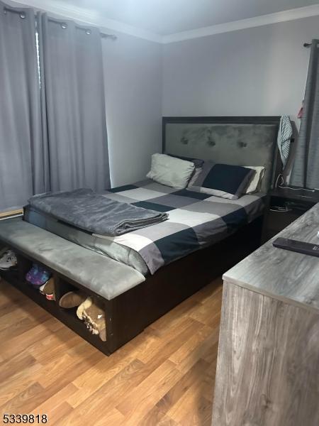 bedroom featuring light wood-type flooring and crown molding