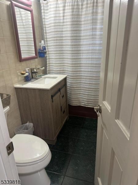 full bathroom featuring toilet, tile patterned flooring, vanity, and tile walls