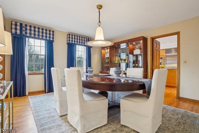 dining space featuring light wood-style flooring and baseboards