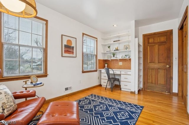 office space featuring a healthy amount of sunlight, built in desk, and wood finished floors