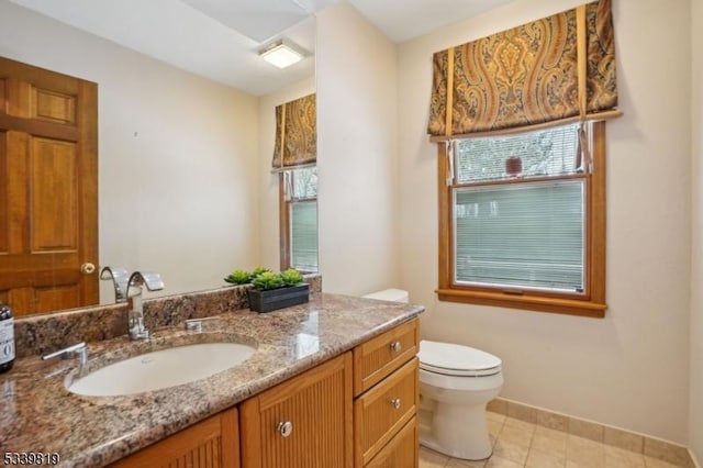 bathroom with toilet, a wealth of natural light, and vanity