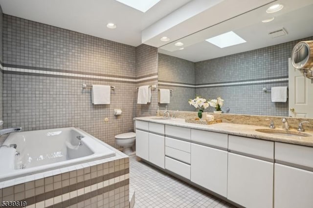 bathroom with a skylight, double vanity, recessed lighting, toilet, and a sink