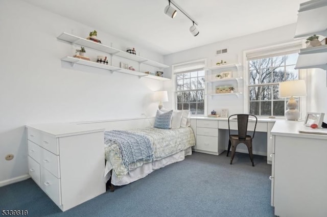 bedroom featuring built in desk, visible vents, dark colored carpet, and track lighting