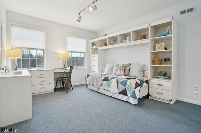 bedroom with rail lighting, visible vents, dark carpet, and baseboards