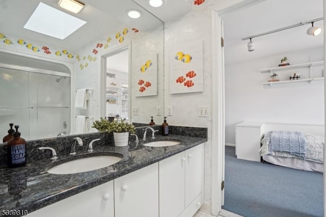 bathroom with a skylight, rail lighting, a sink, and double vanity