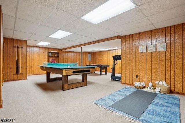 playroom with light carpet, a paneled ceiling, and wooden walls