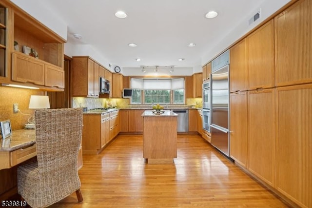 kitchen featuring a center island, stainless steel appliances, visible vents, decorative backsplash, and light wood-style floors