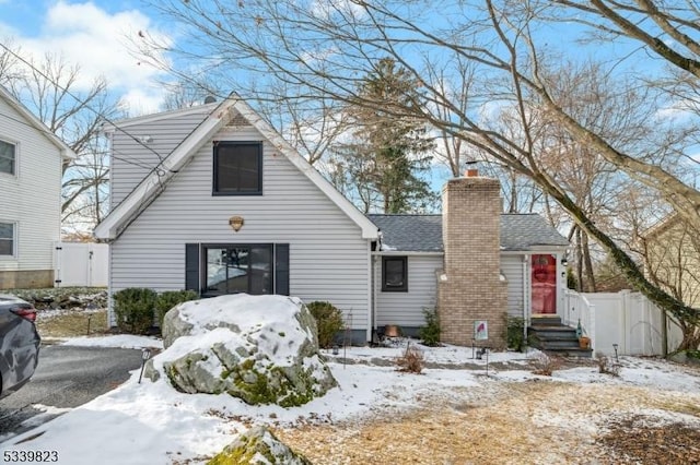 view of front of property with roof with shingles, a chimney, and fence