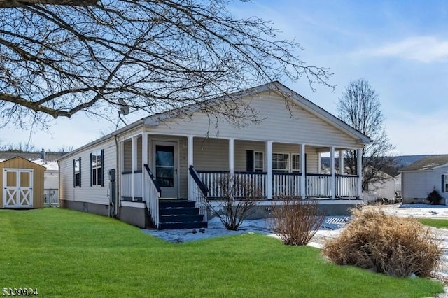 bungalow-style house with an outbuilding, covered porch, a front lawn, and a shed