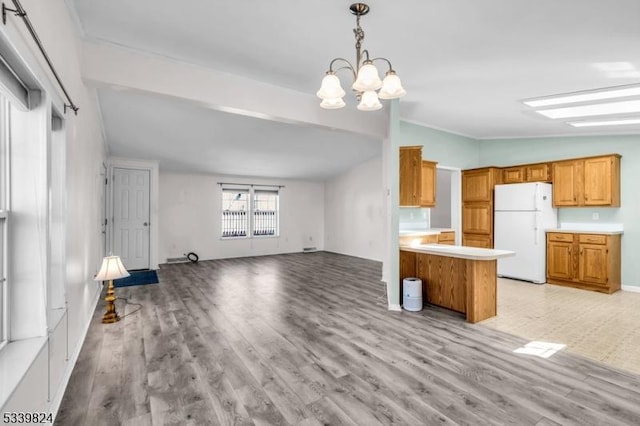 kitchen featuring light wood finished floors, open floor plan, freestanding refrigerator, a peninsula, and light countertops