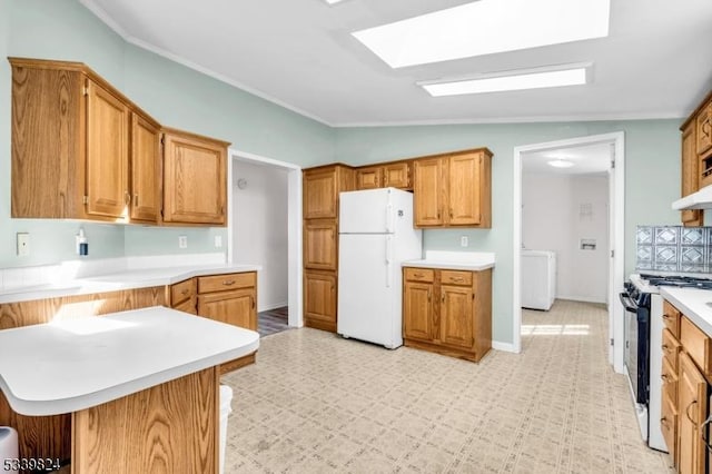 kitchen with washer / dryer, freestanding refrigerator, a peninsula, light countertops, and black range