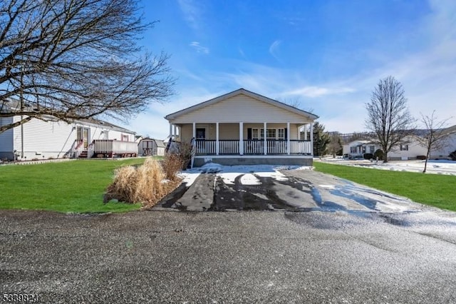 view of front facade featuring driveway, a porch, and a front yard