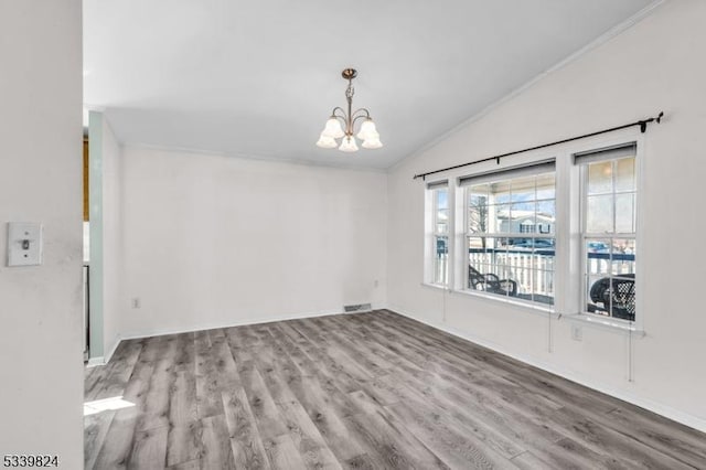 unfurnished room featuring lofted ceiling, an inviting chandelier, visible vents, and wood finished floors