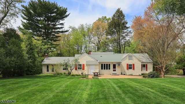 back of house featuring a yard and a chimney