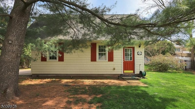 rear view of house featuring a lawn, a shingled roof, and fence