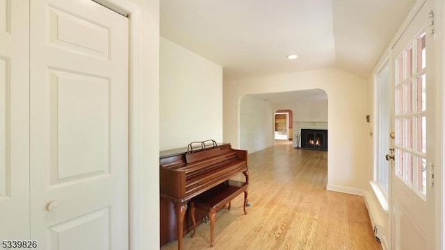 hallway featuring recessed lighting, arched walkways, light wood-style flooring, and baseboards