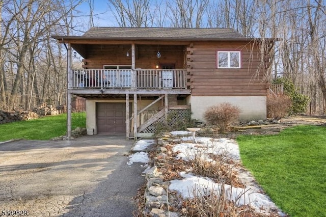 log cabin with an attached garage, aphalt driveway, log exterior, and a front yard