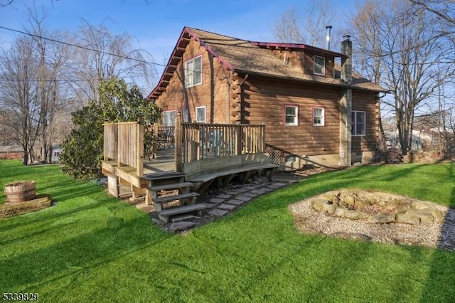 back of house featuring a chimney, a lawn, a deck, and log exterior