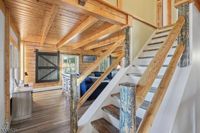 stairs with a barn door, wood ceiling, wood finished floors, wood walls, and beam ceiling