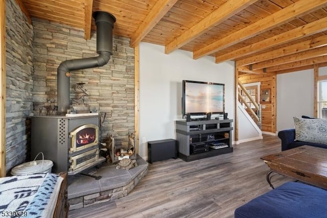 living room with beam ceiling, stairway, wood ceiling, a wood stove, and wood finished floors