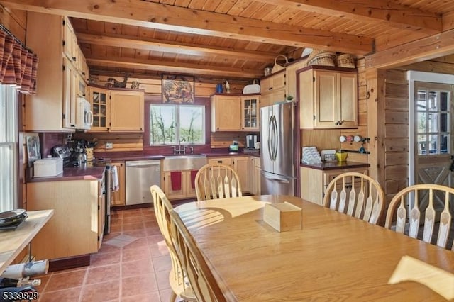 dining area with light tile patterned floors, wood ceiling, beam ceiling, and wood walls