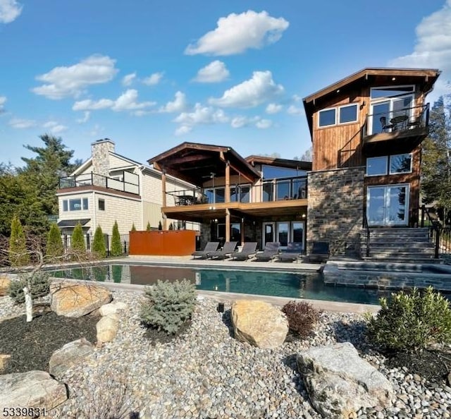 back of house with a patio, a balcony, and an outdoor pool