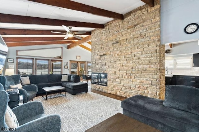 living area featuring beam ceiling, a fireplace, wood finished floors, and a ceiling fan