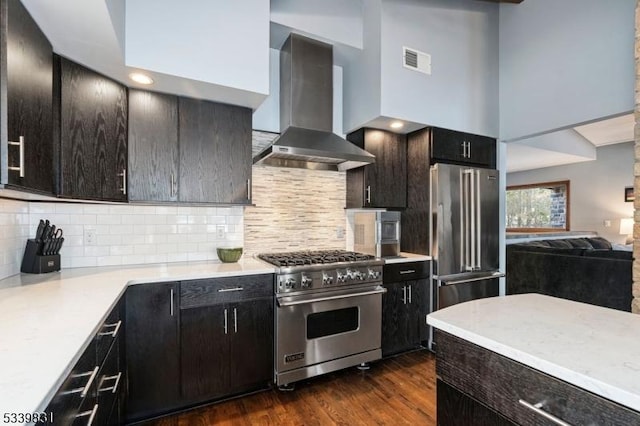 kitchen with visible vents, dark wood finished floors, high quality appliances, light countertops, and wall chimney range hood