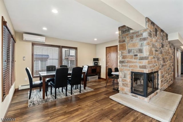 dining space featuring wood finished floors, a stone fireplace, and a wall mounted air conditioner