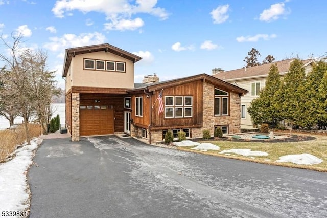 view of front facade featuring aphalt driveway, stone siding, a chimney, and an attached garage