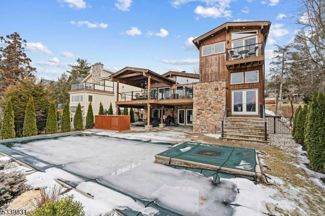 back of property featuring a balcony, a jacuzzi, a patio, and french doors