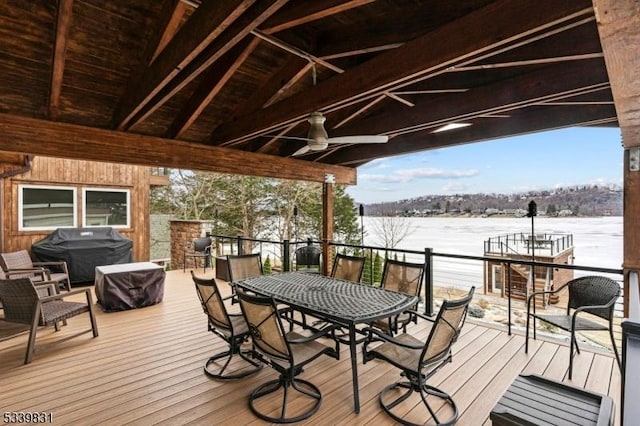 wooden terrace with a ceiling fan, a water view, and a grill