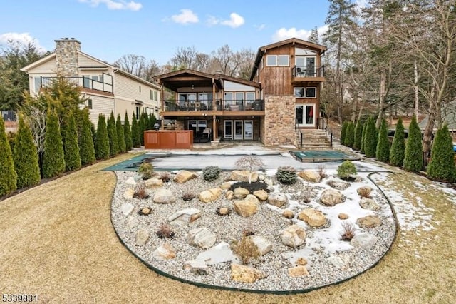 rear view of house featuring a balcony, a patio area, a hot tub, and french doors