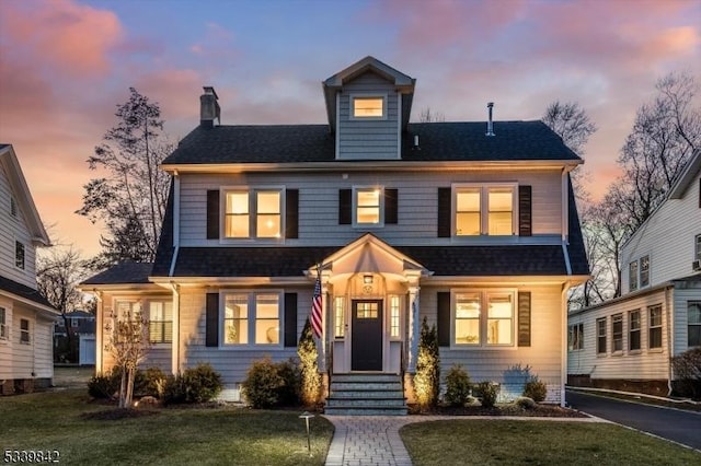 american foursquare style home with a front lawn, roof with shingles, and a chimney