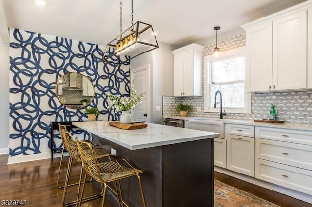 kitchen featuring dark wood-type flooring, a kitchen island, a breakfast bar area, white cabinets, and decorative backsplash