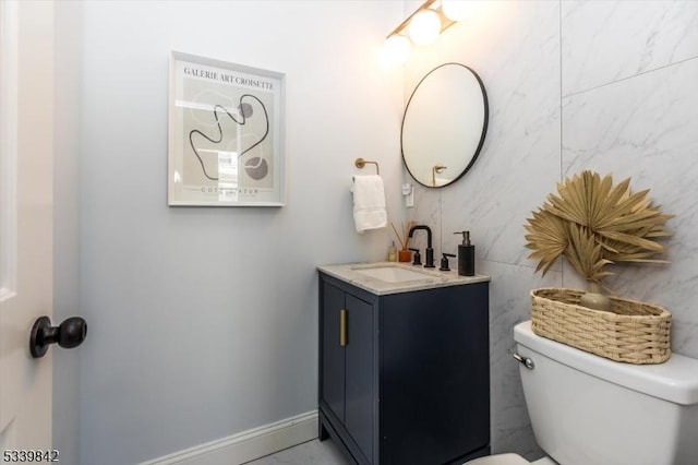 bathroom with toilet, vanity, and baseboards