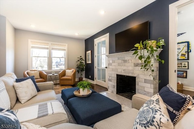 living area featuring recessed lighting, baseboards, a brick fireplace, and wood finished floors