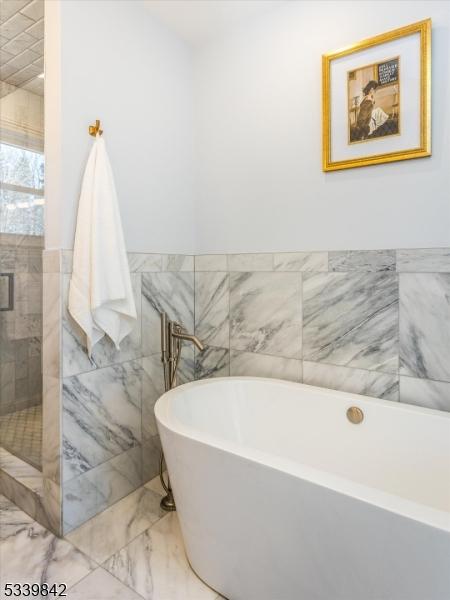 full bathroom with a soaking tub, tile walls, marble finish floor, and a stall shower