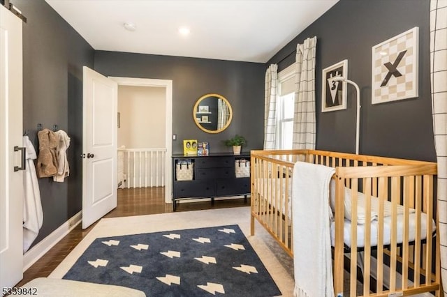 bedroom featuring a barn door, baseboards, and wood finished floors