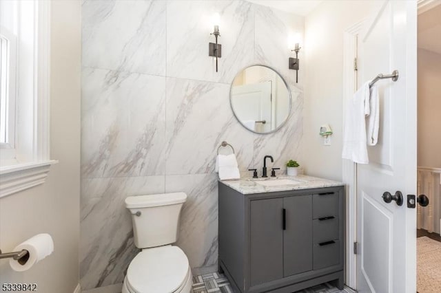 bathroom with tile walls, toilet, and vanity