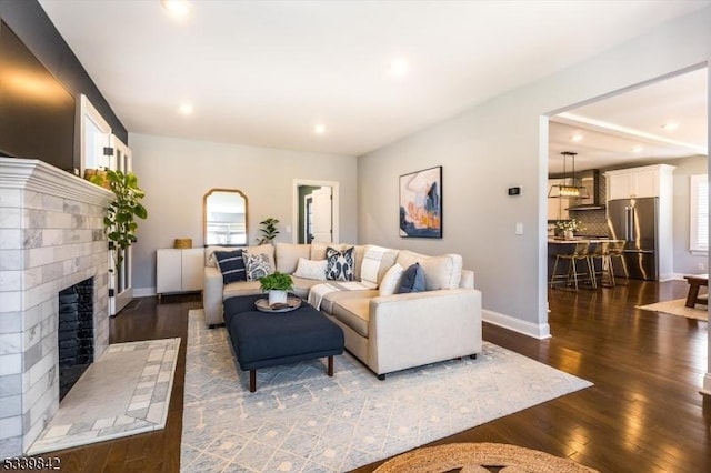 living room with recessed lighting, baseboards, a brick fireplace, and dark wood-style flooring