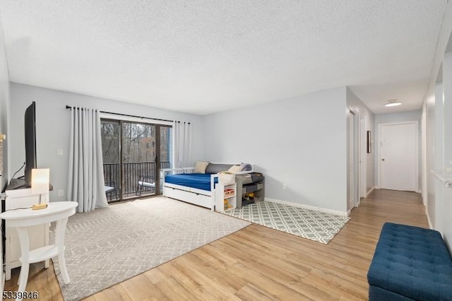 living room featuring a textured ceiling, baseboards, and wood finished floors