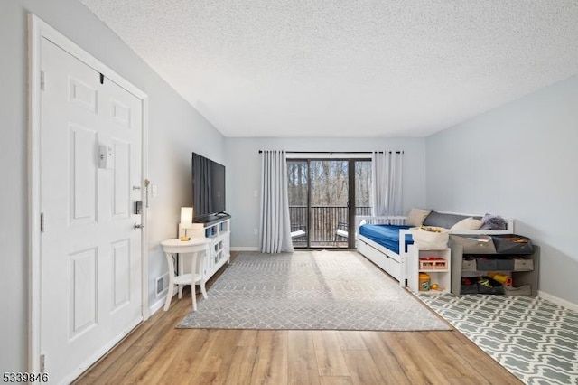 bedroom with visible vents, baseboards, wood finished floors, access to exterior, and a textured ceiling