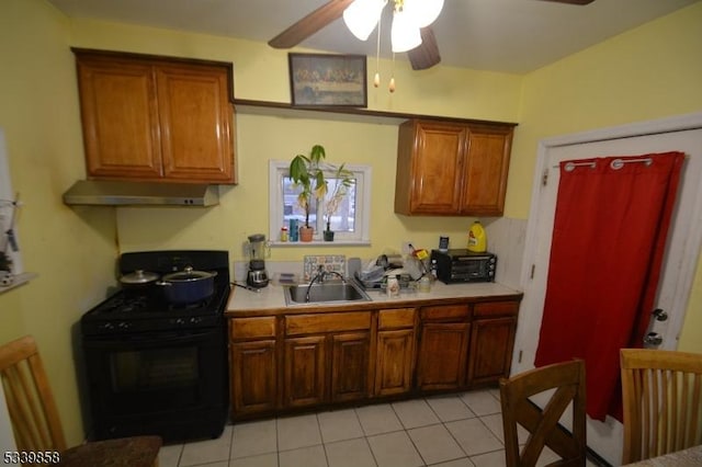 kitchen featuring light countertops, a ceiling fan, black gas stove, a sink, and under cabinet range hood