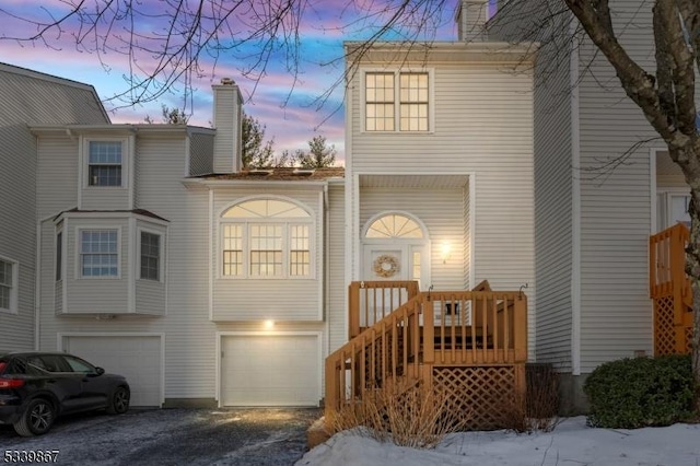 view of front facade featuring a garage, driveway, and a chimney