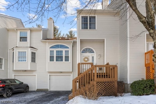 view of front of home featuring a garage, driveway, and a chimney