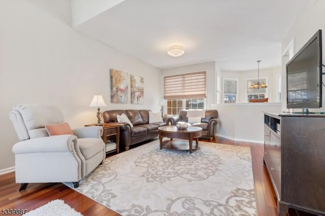 living room featuring a notable chandelier, baseboards, and wood finished floors