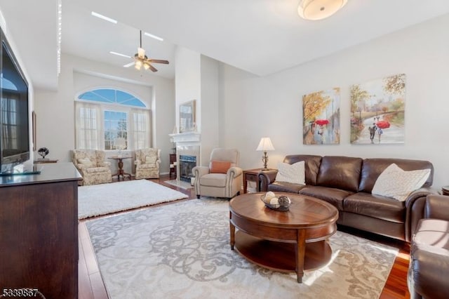 living room featuring wood finished floors, a fireplace with flush hearth, and a ceiling fan