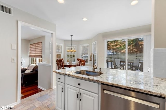 kitchen featuring visible vents, dishwasher, stone tile flooring, white cabinetry, and a sink