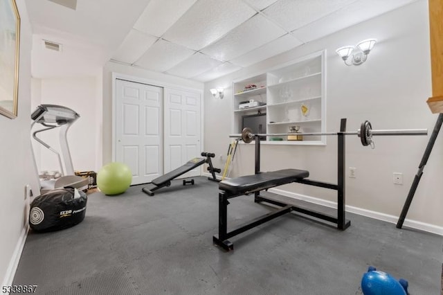 workout area with baseboards, visible vents, and a drop ceiling